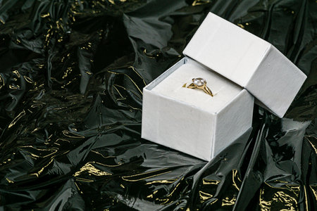 Ring in a jewelry box on background of black plastic for texture and wallpaper