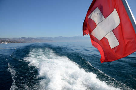 A Swiss flag floats in the wake of a boat from Lake Genevaの写真素材