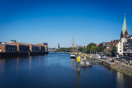 Bremen, Germany - June 29 2019 - View of the river Weser and the historic Schlachte waterfront with the spire of St. Martini church and people at the Kajenmarktのeditorial素材