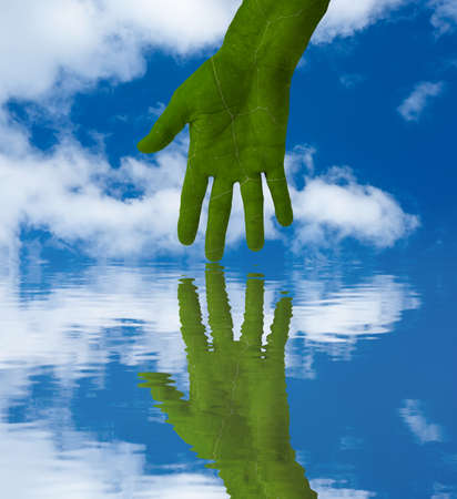 Green hand, with leaf texture, reflected in rippled water. Sky and clouds backgroundの写真素材
