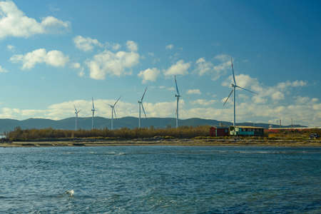 Wind turbine on the mediterranean sea with fishermen shacks. Wind farm near Piombino, Tuscany,...