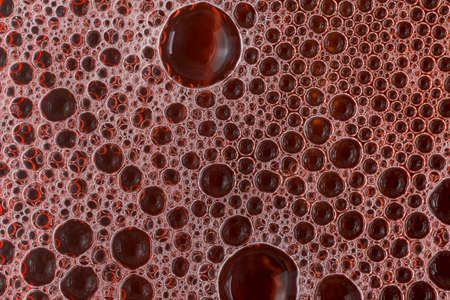 Macro shot of bubbles and soap foam with red liquid, top view, flat background. Texture and reflectionsの写真素材