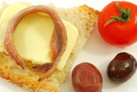 Bread, butter, black olives, anchovies and tomatoesの写真素材