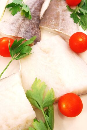Fillets of cod with tomatoes and parsley in the kitchenの写真素材