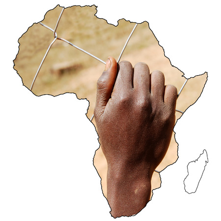 Beyond the borders - image of an African boy clinging to a wire mesh as in a prisonの写真素材