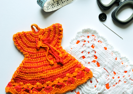 hand knit pot holders next to scissors, tape measure and colored spools