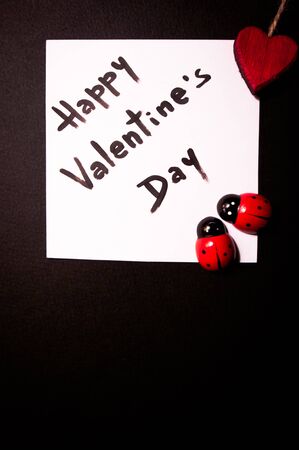 valentine's card displayed with a red heart and two small toy ladybugsの写真素材