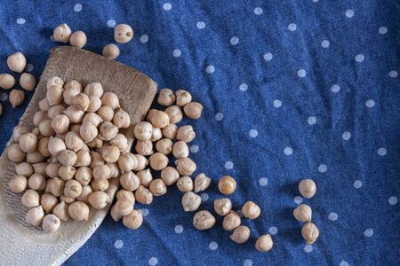 Raw chickpeas in wooden scoops on blue cloth with white dots. Sensation of preparing for traditional stew and have a good time with the family. Lots of texture.の写真素材