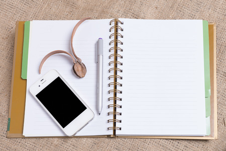 Diary note with smartphone on gunny background (Organizer ,agenda, book, diary)の写真素材