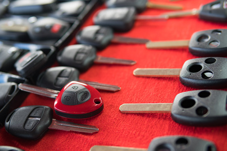 Locksmith stand with variety of car and van keys remote on red backgroundの写真素材