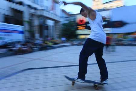 A boy playing with a skateboard in the squareの写真素材