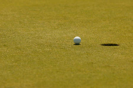 Ein Golfball auf dem Wegg in das Hole, beim puttenの写真素材