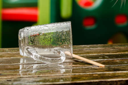Empty wet glass lying outside on a picnic table after a rain shower  の写真素材