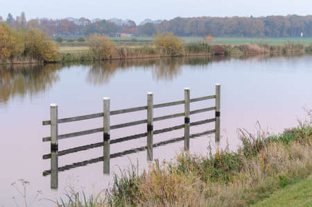 Reflections of a wooden structure in a river on foggy morning near Doesburg in the Netherlands.の写真素材