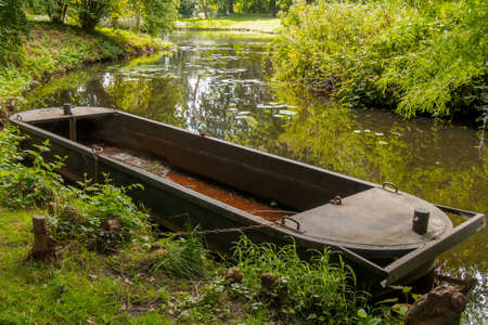 Old rusty boat by riverbank in park