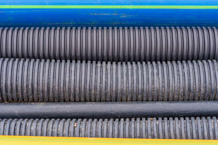 Close up of black plastic drainages, gas and water pipes in an excavation, photographed from aboveの写真素材