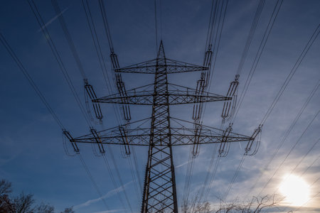 Electricity pylon against a blue sky and evening sunの写真素材