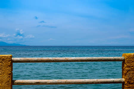 Wonderful view over the blue Mediterranean to the horizon, fence of wood and stone in the foregroundの写真素材