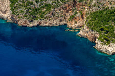 Rocky coast covered with green bushes and the deep blue sea in the west of Zakynthos, Greeceの写真素材
