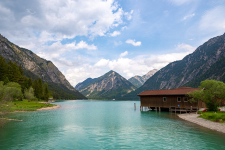 Wonderful view over the Heiterwanger lake framed by mountains and a boathouse on the right sideの写真素材