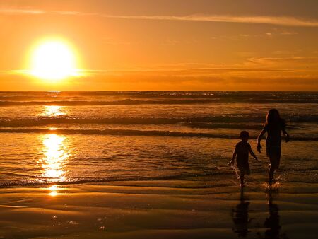 With the sun setting, young people are playing at the beach on the Oregon Coast.の写真素材