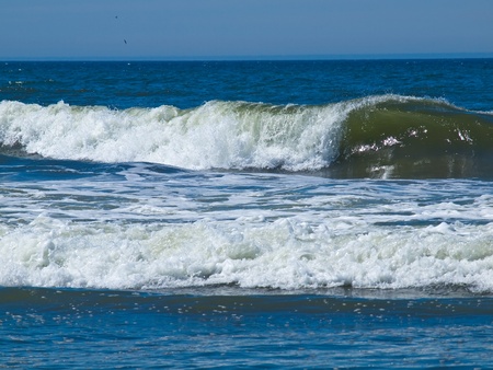 An Ocean Wave Breaking on Shore on a Sunny Dayの写真素材