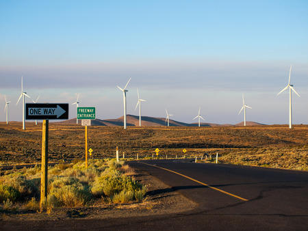 Windmill Farm on a Mountain with One Way Signs Pointing to a Freeway at Duskの写真素材