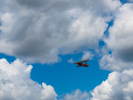 A Biplane in Flight Giving Rides in a Blue Sky and Some Fluffy Cloudsのeditorial素材