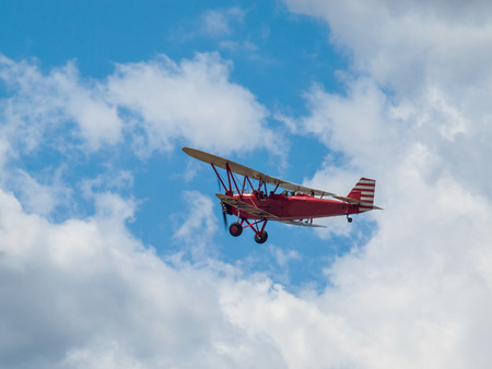 A Biplane in Flight Giving Rides in a Blue Sky and Some Fluffy Clouds