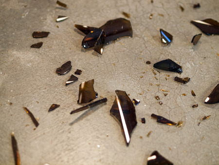 Broken Glass Bottle Pieces on a Cement Floorの写真素材