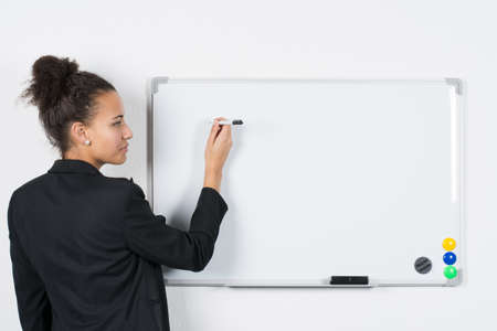 Young business woman writes at a white magnetic boardの写真素材