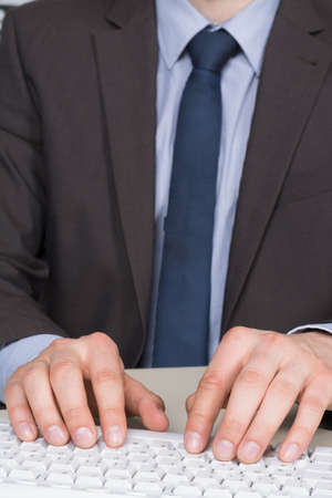Businessman in suit is typing at the computer keyboard.の写真素材