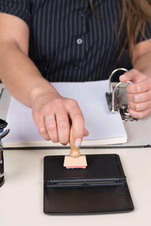 Woman is pressing a stamp at a stamp pad at the desk 