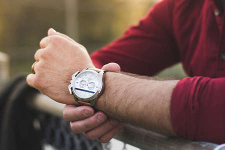 Closeup of young man in casual clothing checking fancy watch