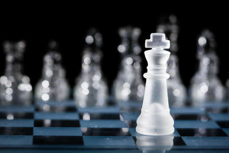 Glass King Chess Piece Facing the Opponent Pieces that are in the Background and out of Focus
