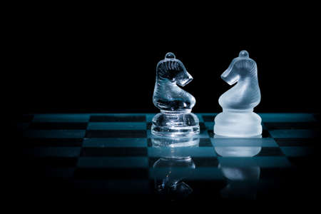 Glass Knight Chess Pieces Face Each Other on a Glass Chessboard with Black Background