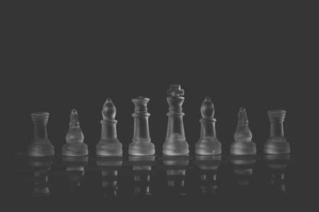 Glass Chess Set Standing on a Chessboard with a Dark Background, including the Rook, Knight, Bishop,...