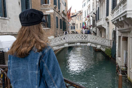 girl standing on a bridge in venice italy, canals in venice with gondolaのeditorial素材