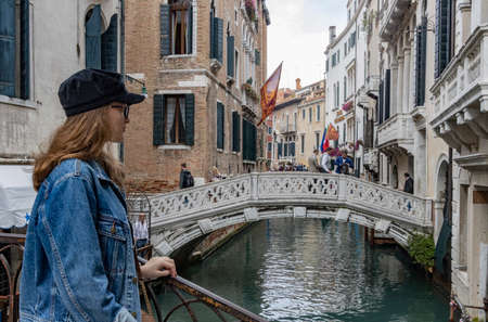 girl standing on a bridge in venice italy, canals in venice with gondolaのeditorial素材