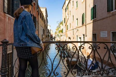girl standing on a bridge in venice italy, canals in venice with gondolaのeditorial素材
