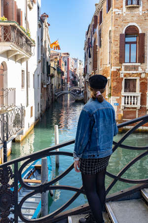 girl standing on a bridge in venice italy, canals in venice with gondolaのeditorial素材