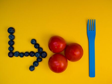 ARROW MADE WITH BLUEBERRIES POINTING AT THE TOMATOESの写真素材