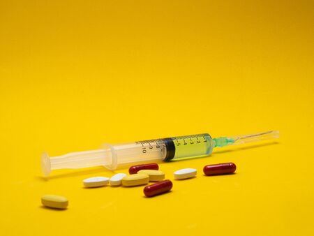 vaccine syringe colored pills with yellow backgroundの写真素材