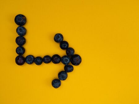 ARROW MADE BLUEBERRIES ON YELLOW BACKGROUNDの写真素材