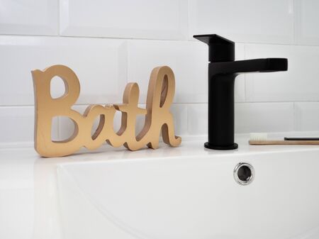 WORD BATH IN GILDED WOOD NEXT TO THE BLACK WASHBASIN TAPの写真素材