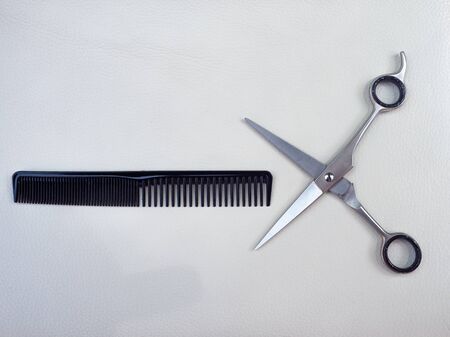 TOOLS OF A HAIRDRESSER, A PAIR OF SCISSORS, A COMB AND A RAZOR ON A WHITE BACKGROUND