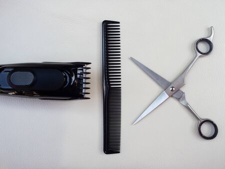TOOLS OF A HAIRDRESSER, A PAIR OF SCISSORS, A COMB AND A RAZOR ON A WHITE BACKGROUND