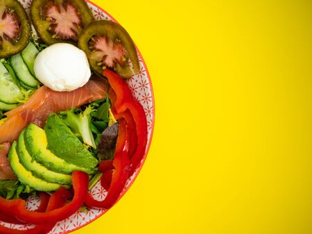 avocado, tomato, egg and salmon salad on a yellow backgroundの写真素材