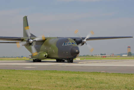 military cargo plane with running engine on taxiway