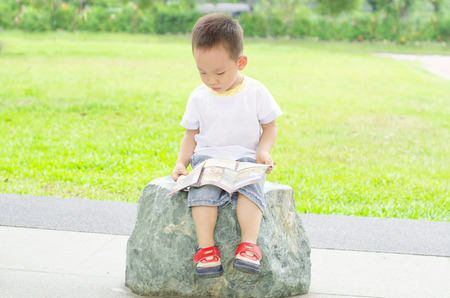 Boy enjoys reading book outdoorの写真素材